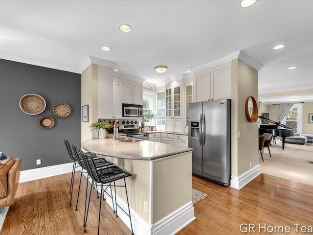 22 Jefferson Ave SE, Grand Rapids, MI 49503 - kitchen with appliances with stainless steel finishes, a peninsula, a sink, crown molding, and a breakfast bar