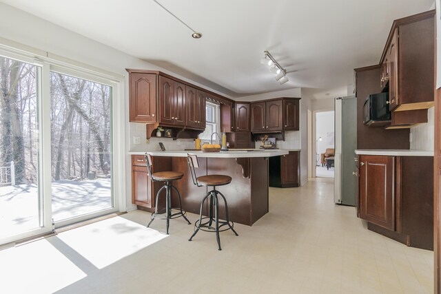 16230 Woodcrest Dr, Spring Lake, MI 49456 - kitchen with a kitchen breakfast bar, black microwave, light countertops, backsplash, and a peninsula