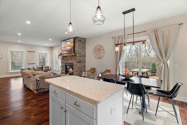 16325 Stones Throw Ln, Union Pier, MI 49129 - kitchen with dark wood-type flooring, decorative light fixtures, a fireplace, and a center island