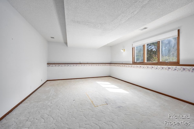spare room featuring a textured ceiling, carpet flooring, baseboards, and visible vents
