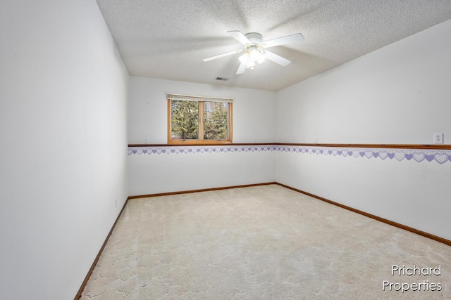 carpeted spare room featuring ceiling fan, baseboards, a textured ceiling, and visible vents
