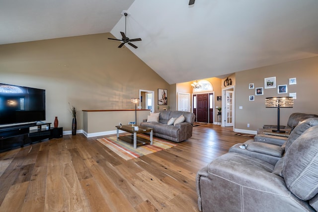 living area with hardwood / wood-style floors, baseboards, high vaulted ceiling, and ceiling fan with notable chandelier