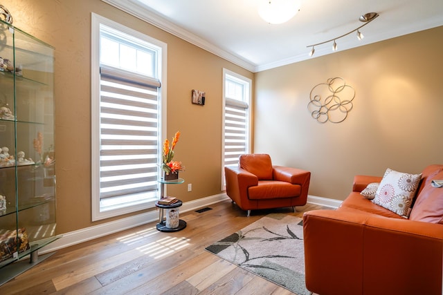 living room featuring crown molding, visible vents, baseboards, and wood-type flooring