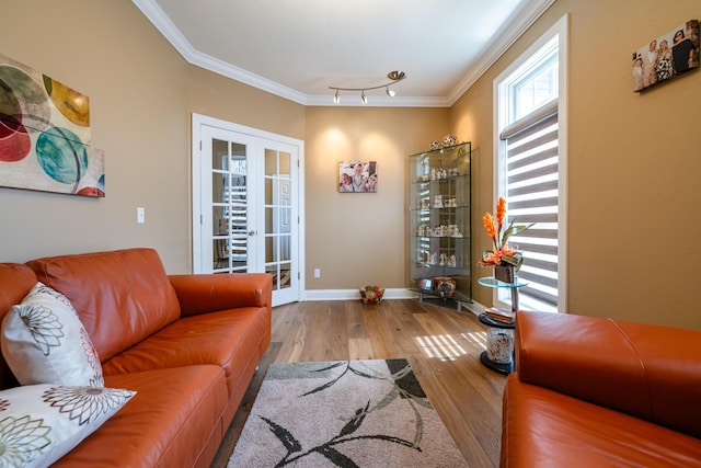 living area with baseboards, wood finished floors, french doors, and crown molding