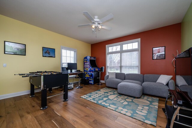 living area with a ceiling fan, wood finished floors, and baseboards