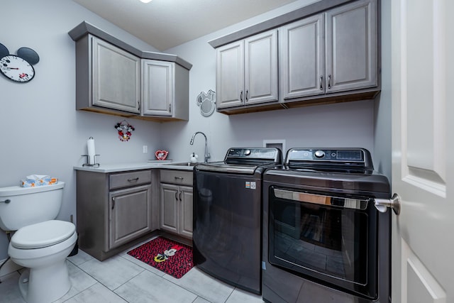 clothes washing area featuring light tile patterned flooring, washing machine and clothes dryer, cabinet space, and a sink
