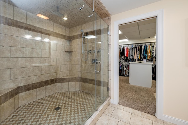 bathroom with tile patterned flooring, a shower stall, and a spacious closet
