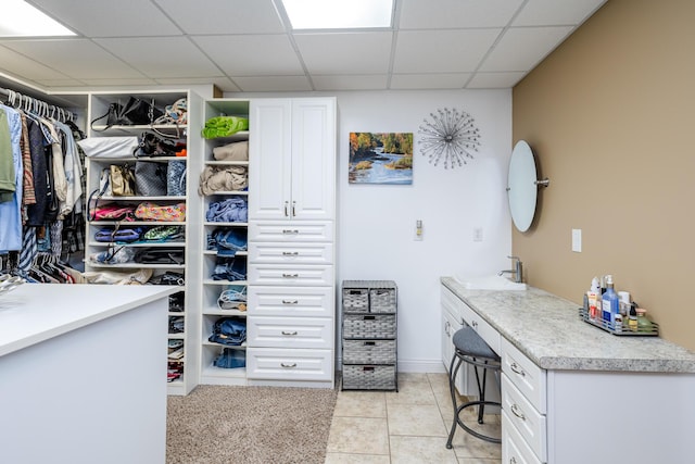 spacious closet featuring light tile patterned flooring, a paneled ceiling, and a sink