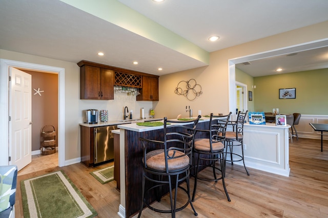 bar featuring a sink, light wood-type flooring, dishwasher, indoor wet bar, and recessed lighting