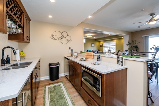 kitchen featuring a sink, a peninsula, stainless steel appliances, and light wood-style floors