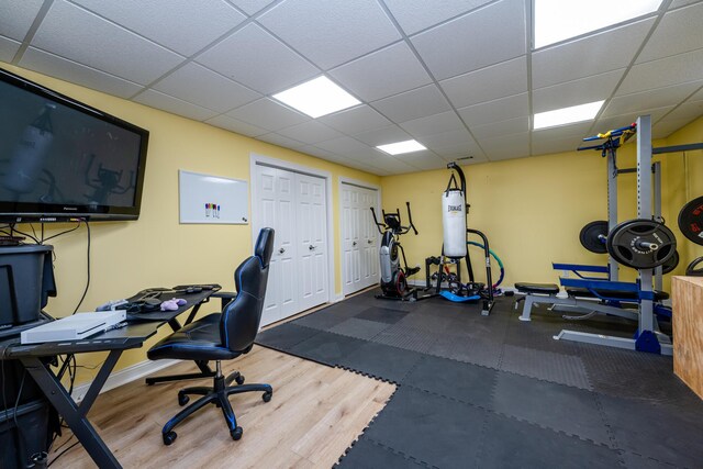 workout room with baseboards, wood finished floors, and a drop ceiling
