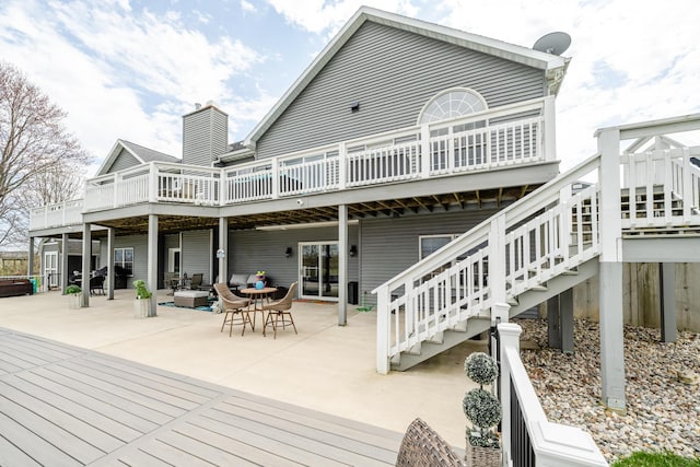 back of property featuring a chimney, a deck, a patio area, outdoor lounge area, and stairway