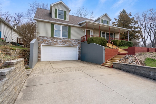 10951 N Waldron Rd, Jerome, MI 49249 - view of front facade featuring driveway, stone siding, an attached garage, a porch, and stairs