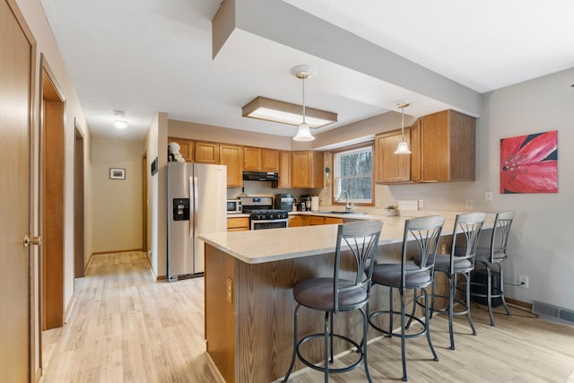 10951 N Waldron Rd, Jerome, MI 49249 - kitchen featuring appliances with stainless steel finishes, light wood-style flooring, a peninsula, under cabinet range hood, and visible vents