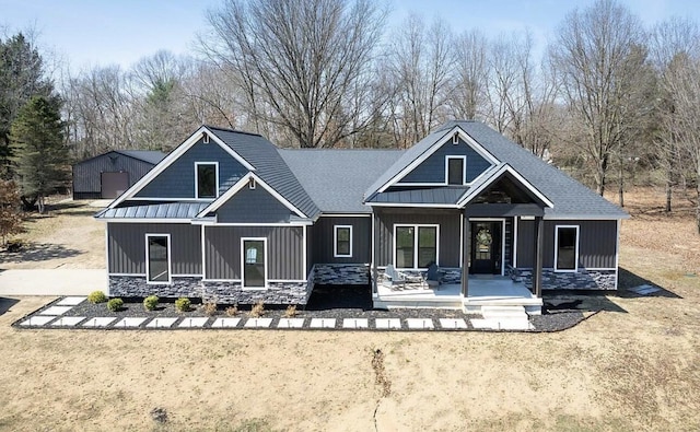 8477 84th St SE, Alto, MI 49302 - rear view of house featuring a standing seam roof, a porch, stone siding, metal roof, and board and batten siding