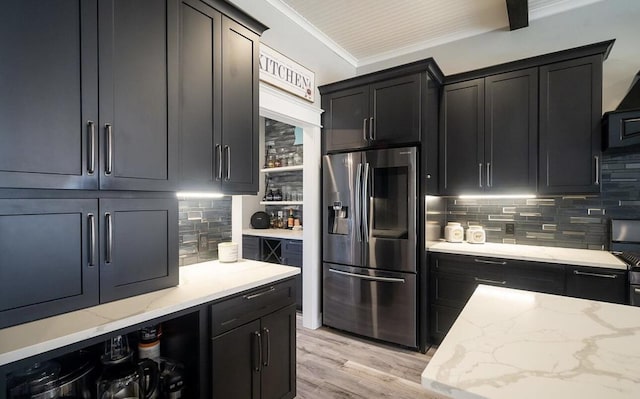 8477 84th St SE, Alto, MI 49302 - kitchen with stainless steel fridge with ice dispenser, dark cabinetry, light wood-style flooring, backsplash, and light stone countertops