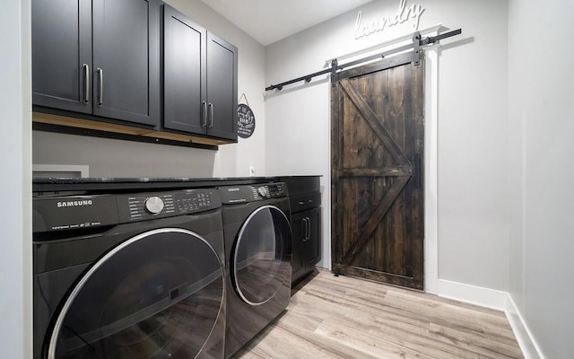 8477 84th St SE, Alto, MI 49302 - washroom featuring a barn door, separate washer and dryer, light wood-type flooring, cabinet space, and baseboards