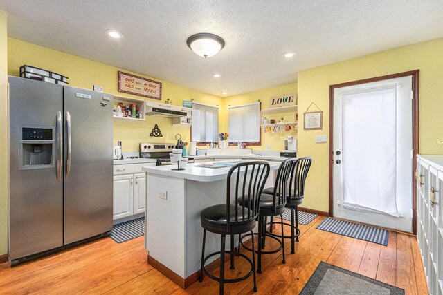 66100 Dolans Ave, Vandalia, MI 49095 - kitchen featuring stainless steel appliances, light countertops, under cabinet range hood, and a kitchen bar