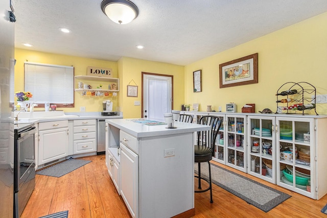66100 Dolans Ave, Vandalia, MI 49095 - kitchen featuring a sink, a breakfast bar area, electric range oven, light wood finished floors, and white cabinets