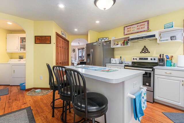 66100 Dolans Ave, Vandalia, MI 49095 - kitchen with under cabinet range hood, open shelves, a breakfast bar, washing machine and dryer, and appliances with stainless steel finishes