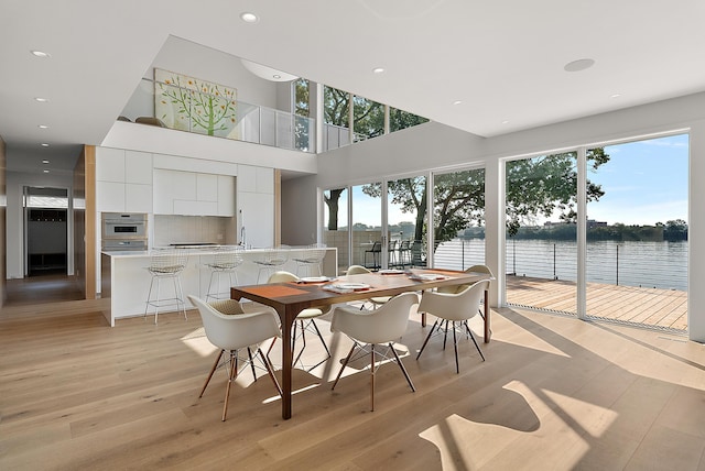 602 Lawn Ave, Holland, MI 49424 - dining area with recessed lighting, light wood-style flooring, a water view, and a towering ceiling