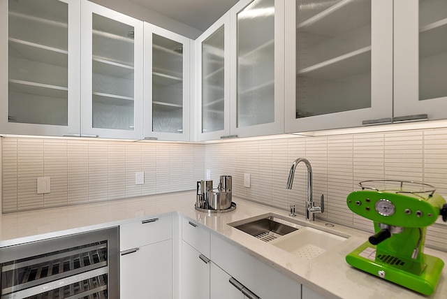 602 Lawn Ave, Holland, MI 49424 - kitchen with wine cooler, a sink, white cabinetry, decorative backsplash, and glass insert cabinets
