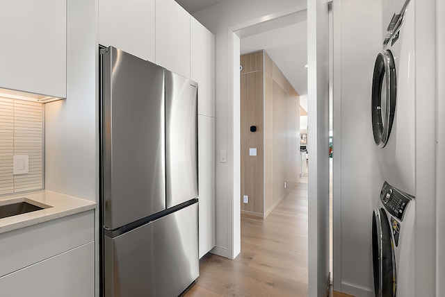 602 Lawn Ave, Holland, MI 49424 - kitchen with light wood-style floors, modern cabinets, white cabinets, stacked washer and clothes dryer, and freestanding refrigerator