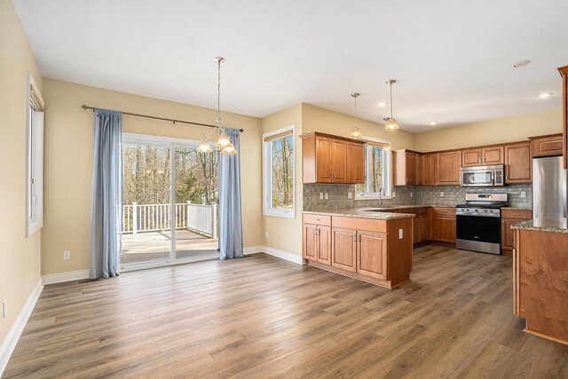 8560 Western Woods Dr, Kalamazoo, MI 49009 - kitchen featuring stainless steel appliances, wood finished floors, baseboards, and decorative backsplash