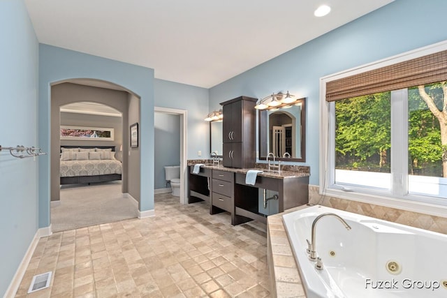 17180 Shore Oaks W Ln, Holland, MI 49424 - ensuite bathroom featuring vanity, a tub with jets, and stone finish flooring