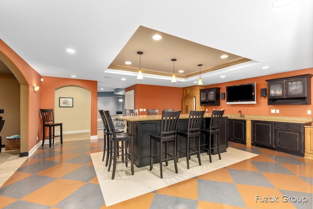 17180 Shore Oaks W Ln, Holland, MI 49424 - indoor wet bar with a tray ceiling, recessed lighting, pendant lighting, arched walkways, and light floors