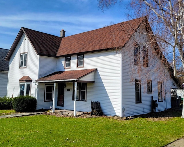 traditional home with a chimney, a porch, a shingled roof, and a front lawn