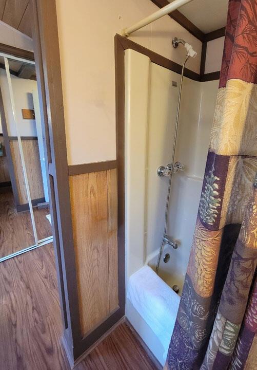 bathroom featuring wainscoting, shower / tub combo, and wood finished floors