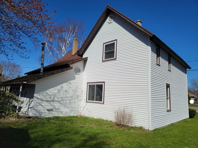 view of side of property with a lawn and a chimney