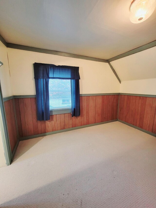 bonus room featuring vaulted ceiling, wooden walls, wainscoting, and carpet floors