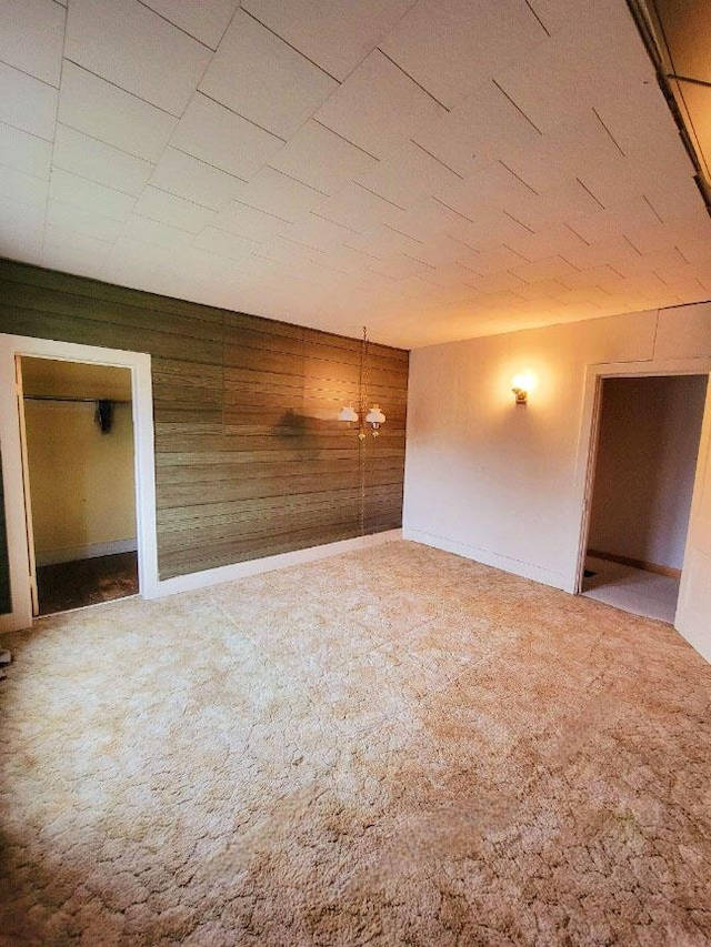 carpeted spare room with wooden walls