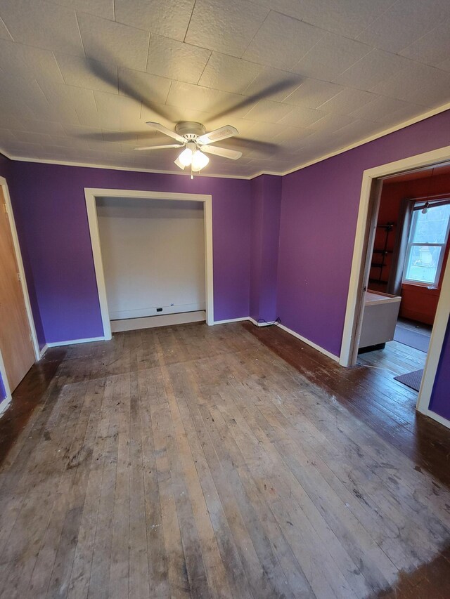 interior space with wood-type flooring, crown molding, a ceiling fan, and baseboards