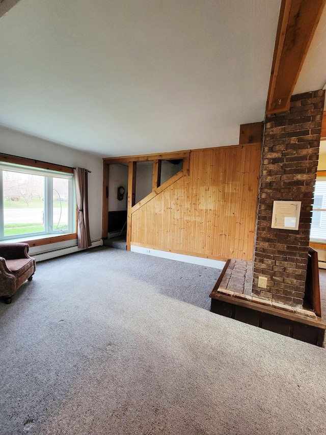 unfurnished living room with baseboards, wood walls, and carpet flooring