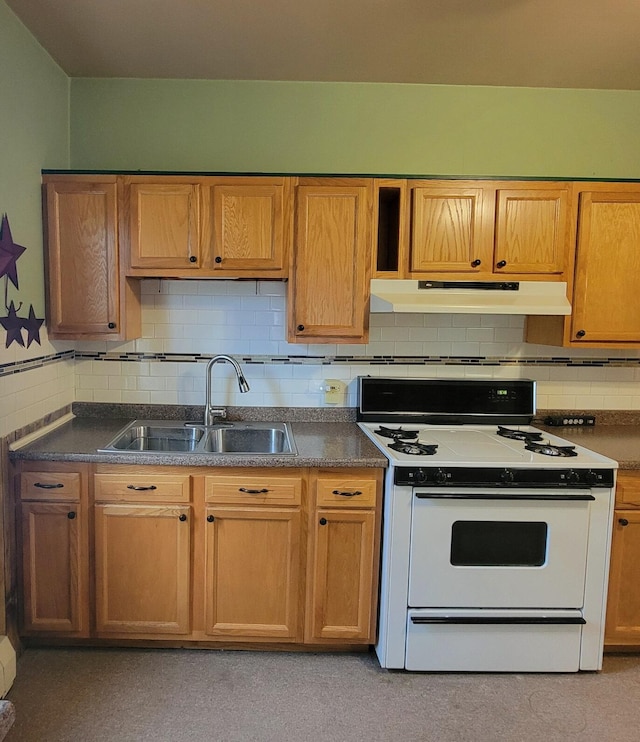 kitchen with decorative backsplash, under cabinet range hood, dark countertops, a sink, and white gas stove