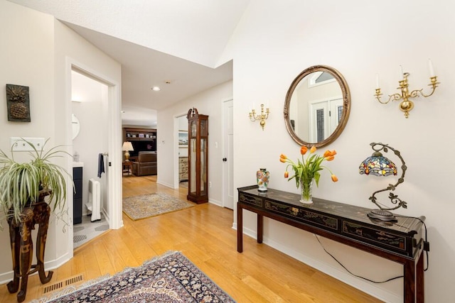 hallway featuring recessed lighting, lofted ceiling, visible vents, light wood-style floors, and baseboards