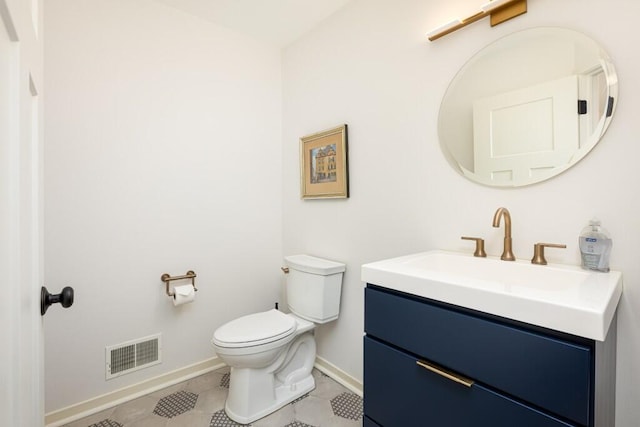 half bath featuring tile patterned flooring, visible vents, toilet, vanity, and baseboards