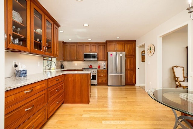 kitchen with brown cabinets, light wood-style floors, appliances with stainless steel finishes, and a sink