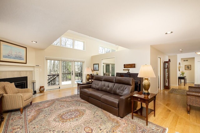 living room featuring light wood-type flooring, a tile fireplace, baseboards, visible vents, and recessed lighting