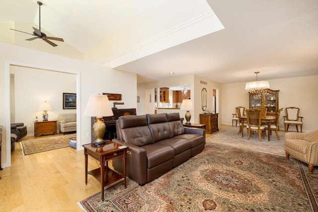 living room with ceiling fan with notable chandelier, vaulted ceiling, visible vents, and light wood-style floors