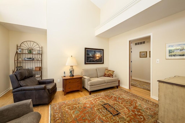 living room with light wood-type flooring, visible vents, and baseboards