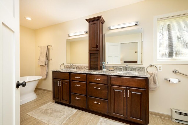 full bath featuring a baseboard radiator, baseboards, a sink, and double vanity