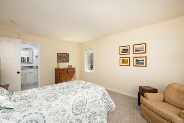 bedroom with ensuite bath, light carpet, a sink, and baseboards