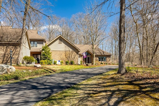 view of front of home with driveway and roof with shingles