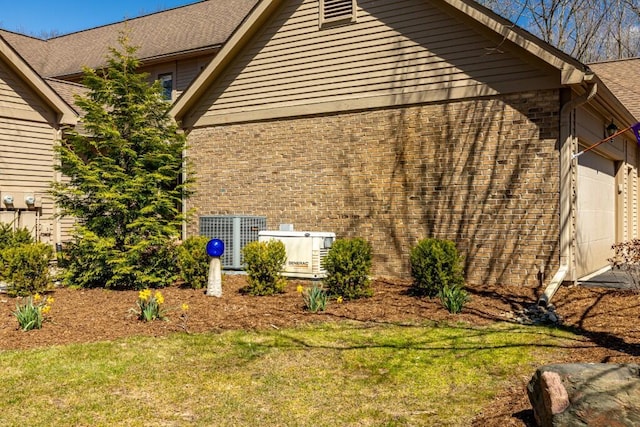 view of side of property with cooling unit, brick siding, a garage, and a lawn