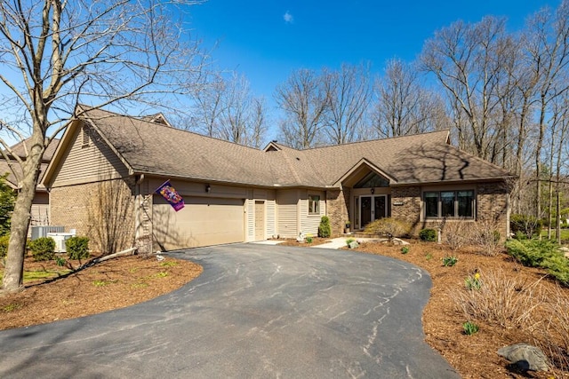 ranch-style house featuring brick siding, an attached garage, driveway, and roof with shingles