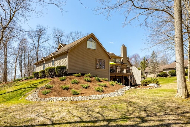 rear view of property with a yard, a chimney, and a deck